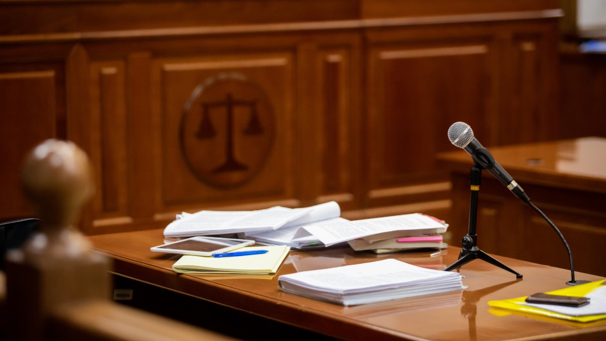 Courtroom desk with legal documents and scales of justice seal, regulatory compliance context